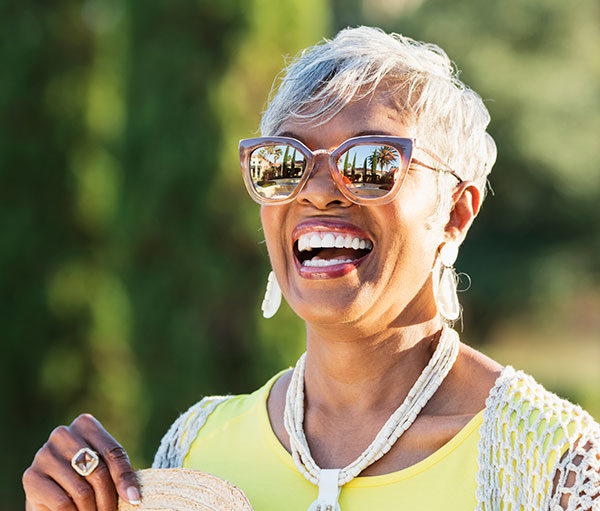 senior African-American woman in her 70s wearing sunglasses on a sunny day.