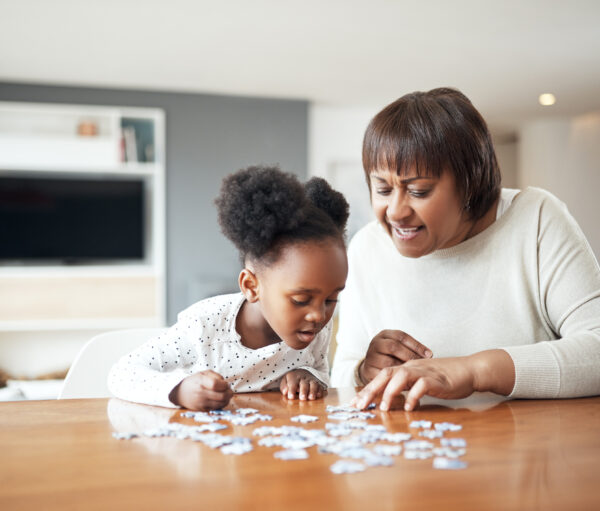 Shot of a little girl building a puzzle with her grandmother at home