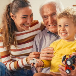 Portrait of a Small Family of a Mother, a Son and a Grandfather Watching TV Together in the Living Room. Family Generations Connecting and Bonding by Spending Time Together, Discussing and Having Fun