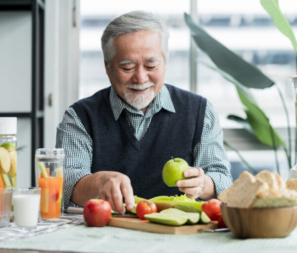 Asian elder senior male vlog teach cooking on mobile phone. Male old man vlogs, Old chef records a video tutorial on his phone about preparing heathy salad and infused water at home